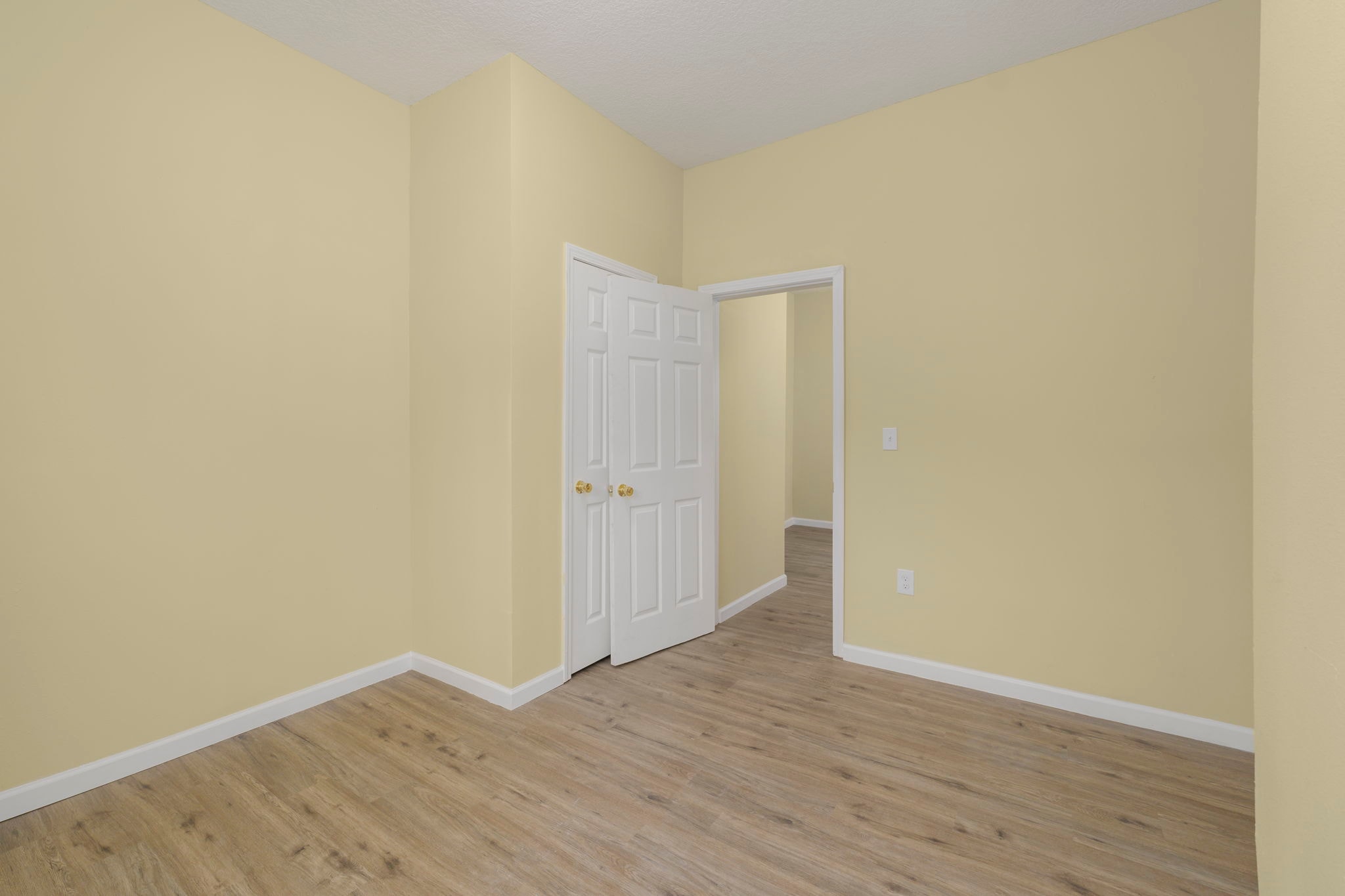 Bedroom with yellow walls, closet doors and wood flooring