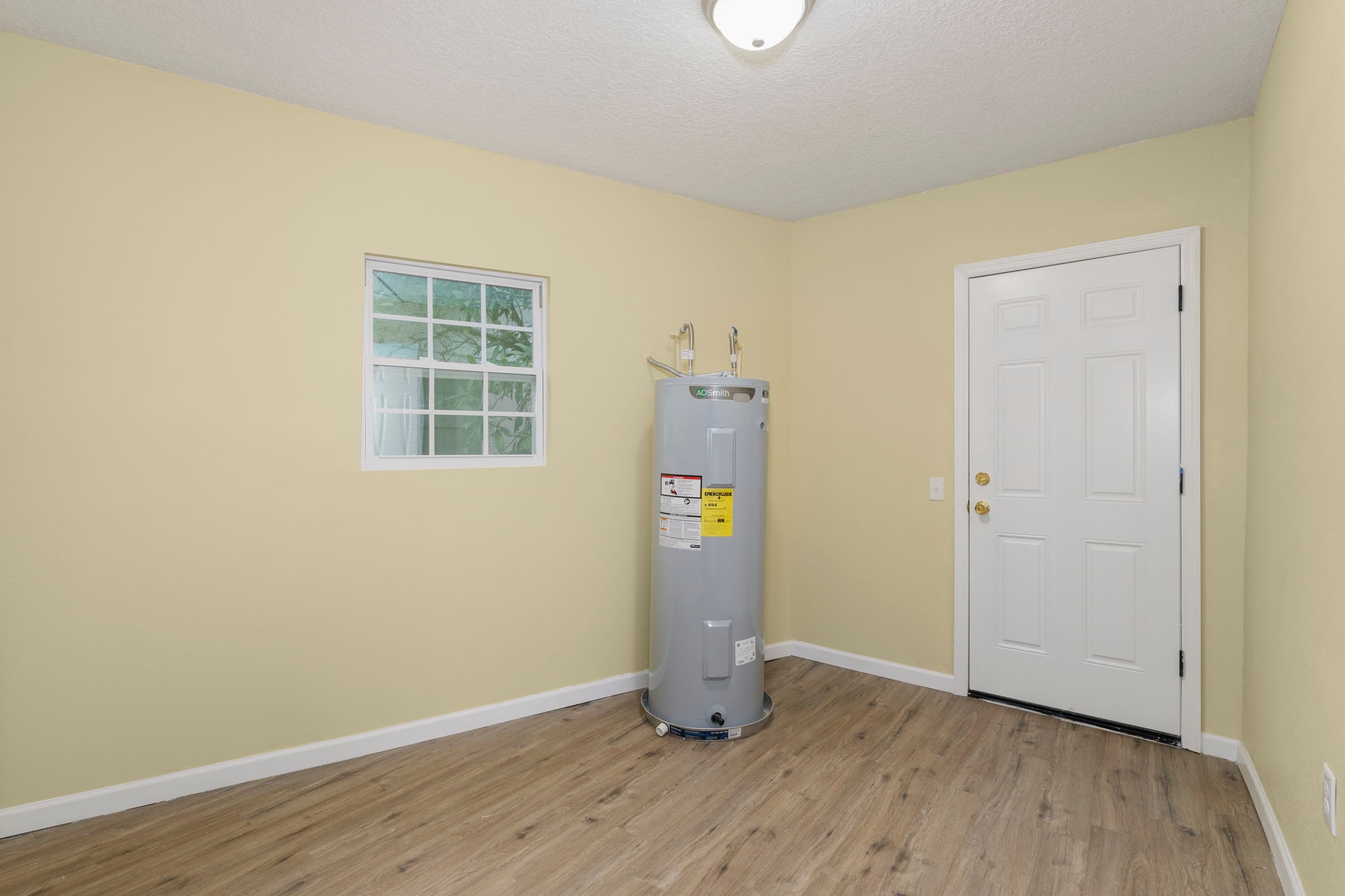 Utility room with new water heater, wood flooring and back door