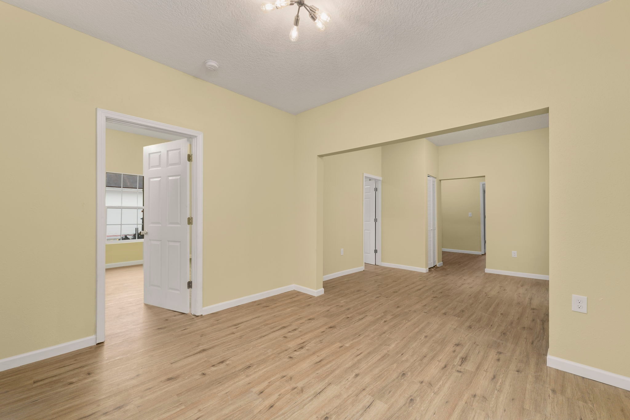 Open living area with wood floors and multiple doorways