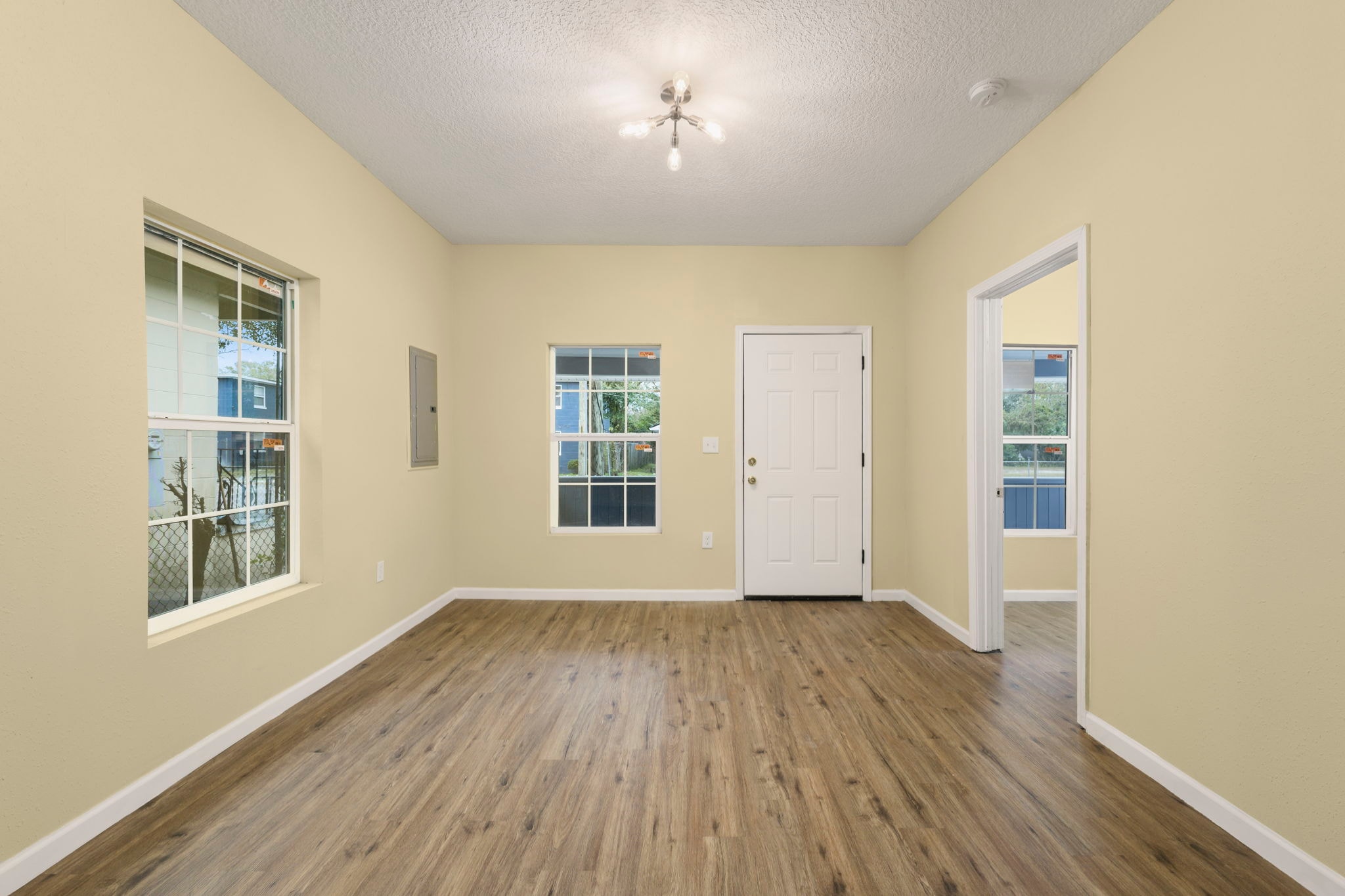 Spacious room with yellow walls, hardwood floors and windows