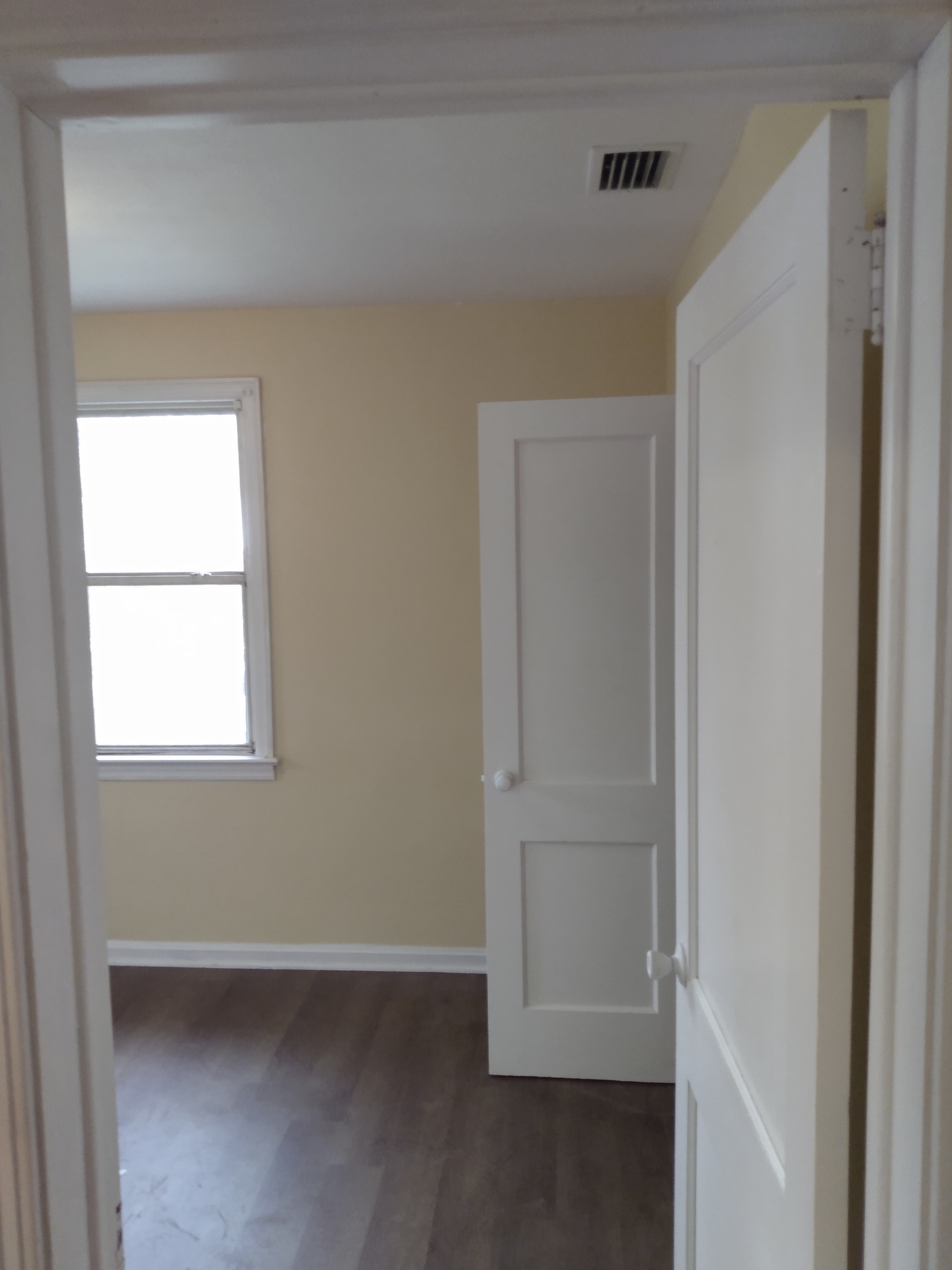 Hallway view into bedroom – cream walls, white panel doors, dark wood flooring
