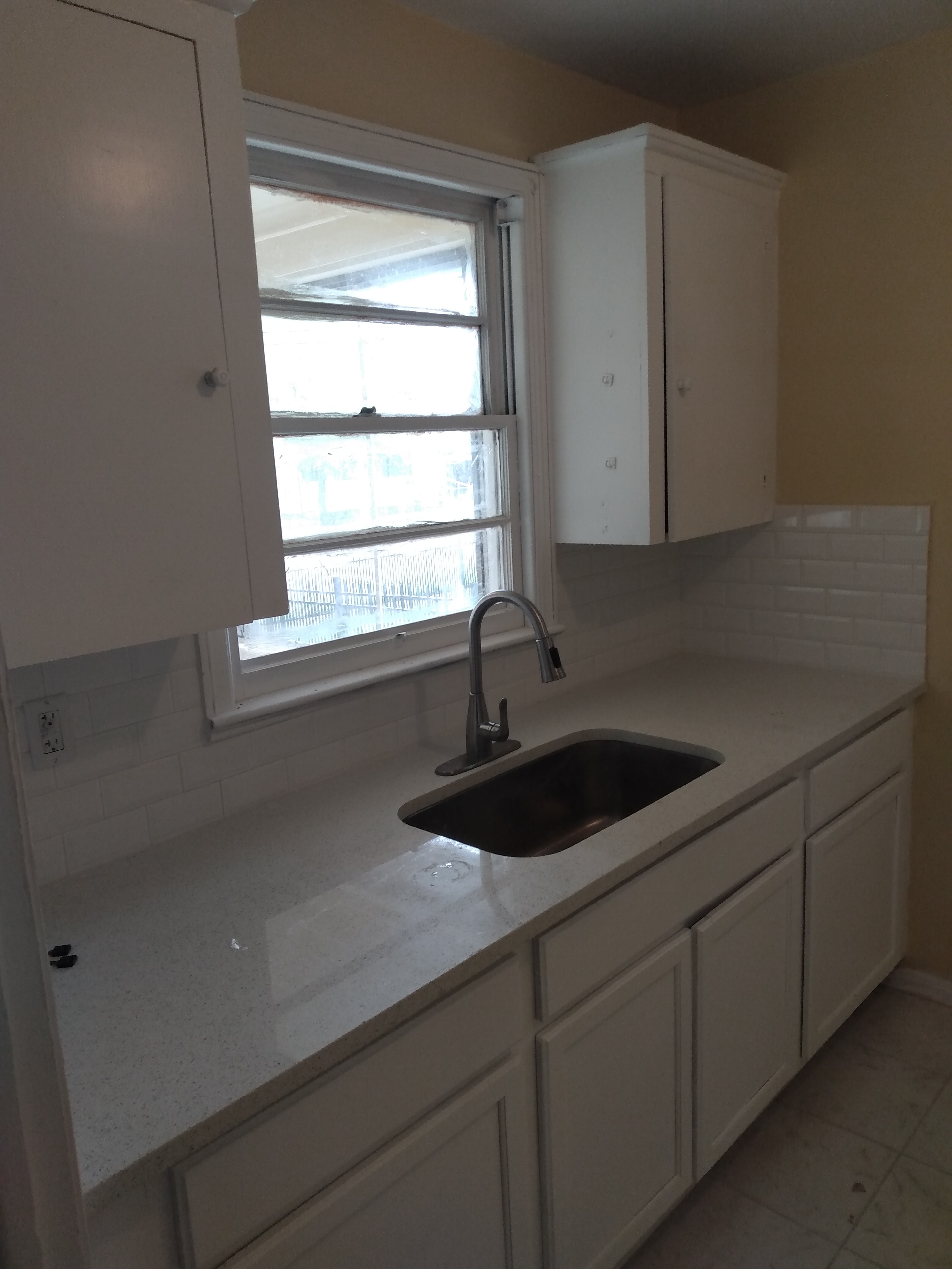 Kitchen sink – white cabinets, quartz countertop, black undermount sink, chrome faucet, subway tile