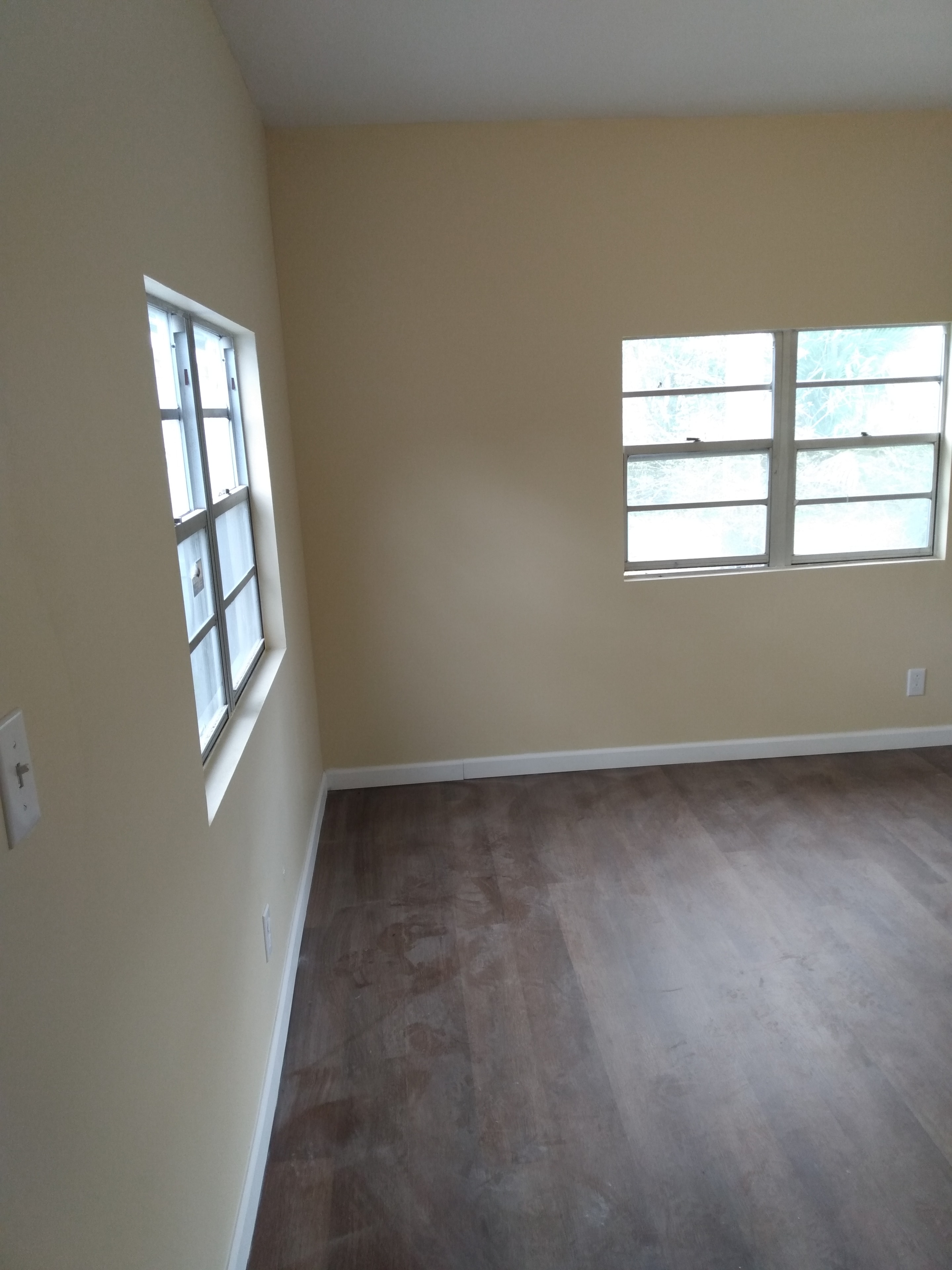 Bright bedroom – cream walls, two large windows, dark wood flooring