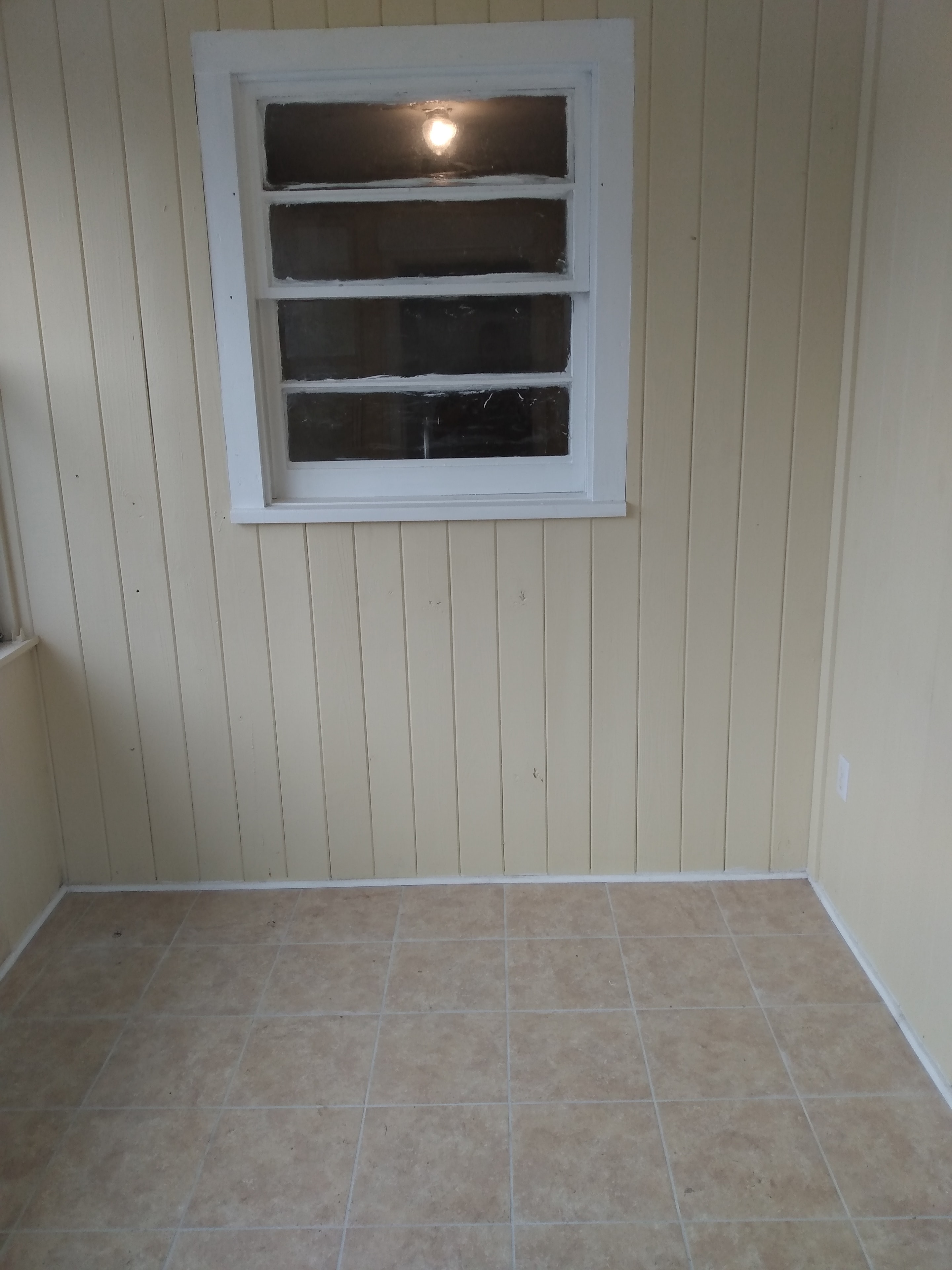 Enclosed porch – vertical wood paneling, tile floor, white-framed window