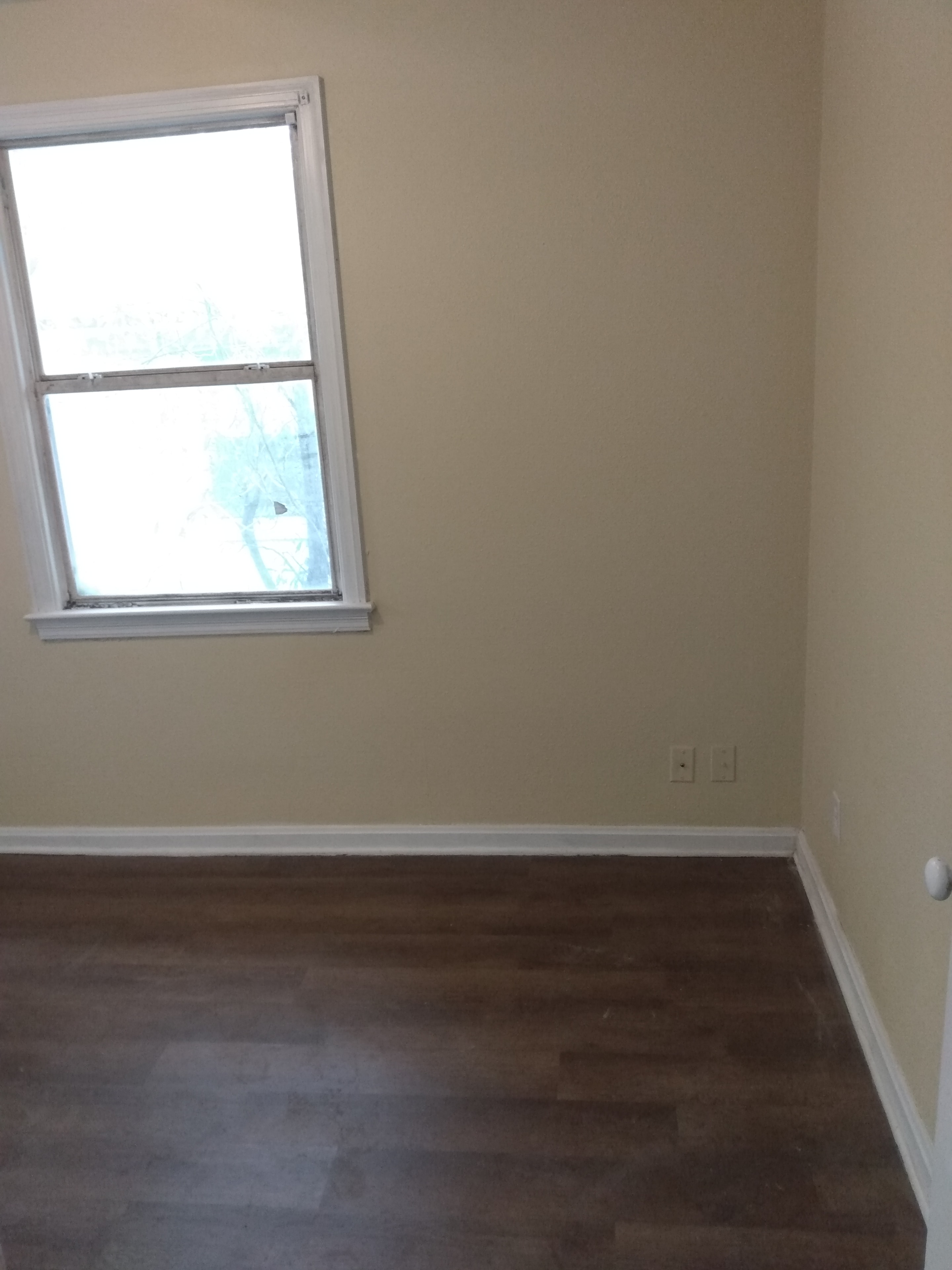 Bedroom – cream walls, single window, dark wood flooring