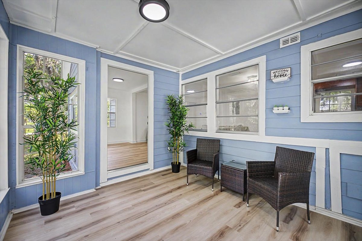 Sunroom – blue shiplap walls, white coffered ceiling, LVP flooring, rattan seating and tropical plants