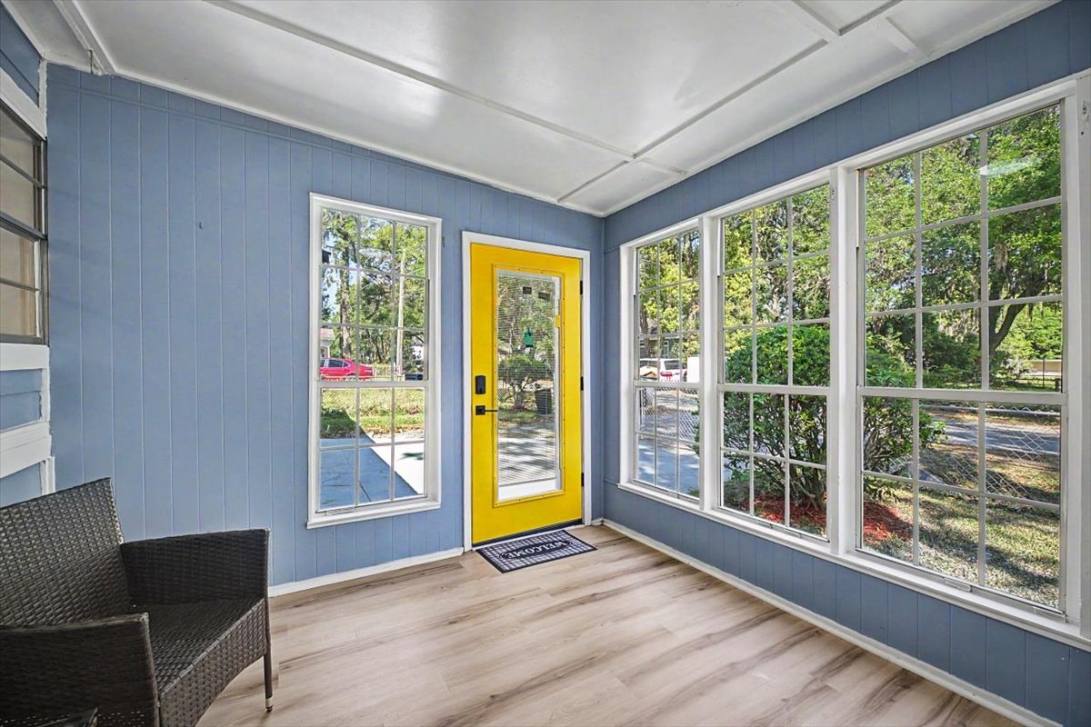 Sunroom entry – yellow front door with sidelights, wraparound windows, LVP flooring