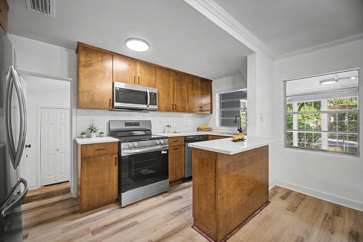 Kitchen with island – walnut cabinets, white quartz counters, subway tile backsplash, stainless range and dishwasher