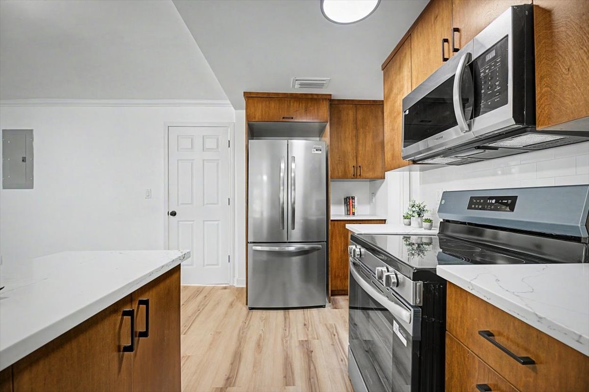 Kitchen refrigerator alcove – stainless French-door fridge, walnut cabinetry, quartz island counter, stainless range
