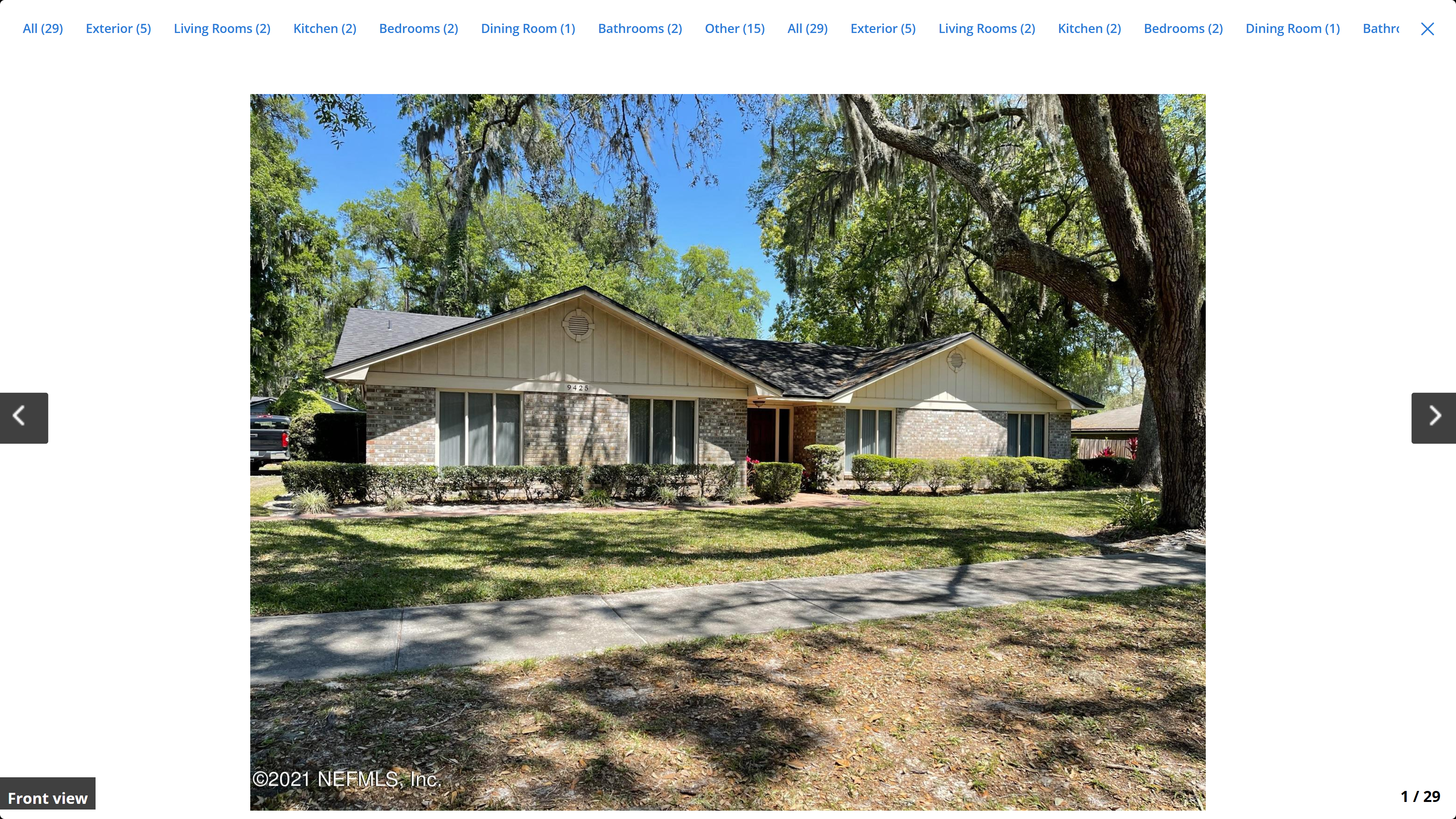 9425 Beauclerc Oaks Dr – front view, brick and board-and-batten ranch home under Spanish moss oaks