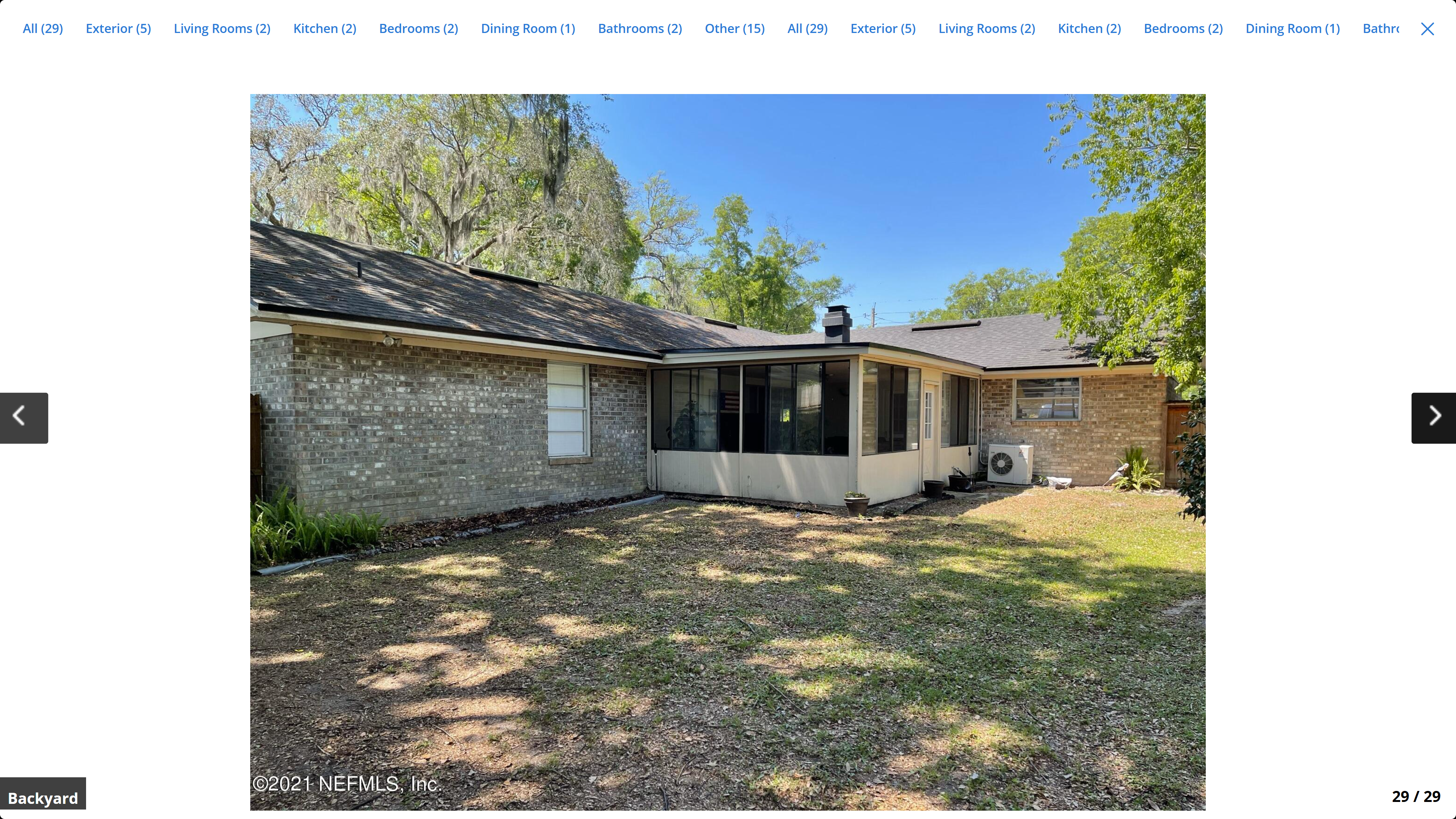 Rear exterior – brick back wall, screened porch addition, AC unit, mature tree canopy