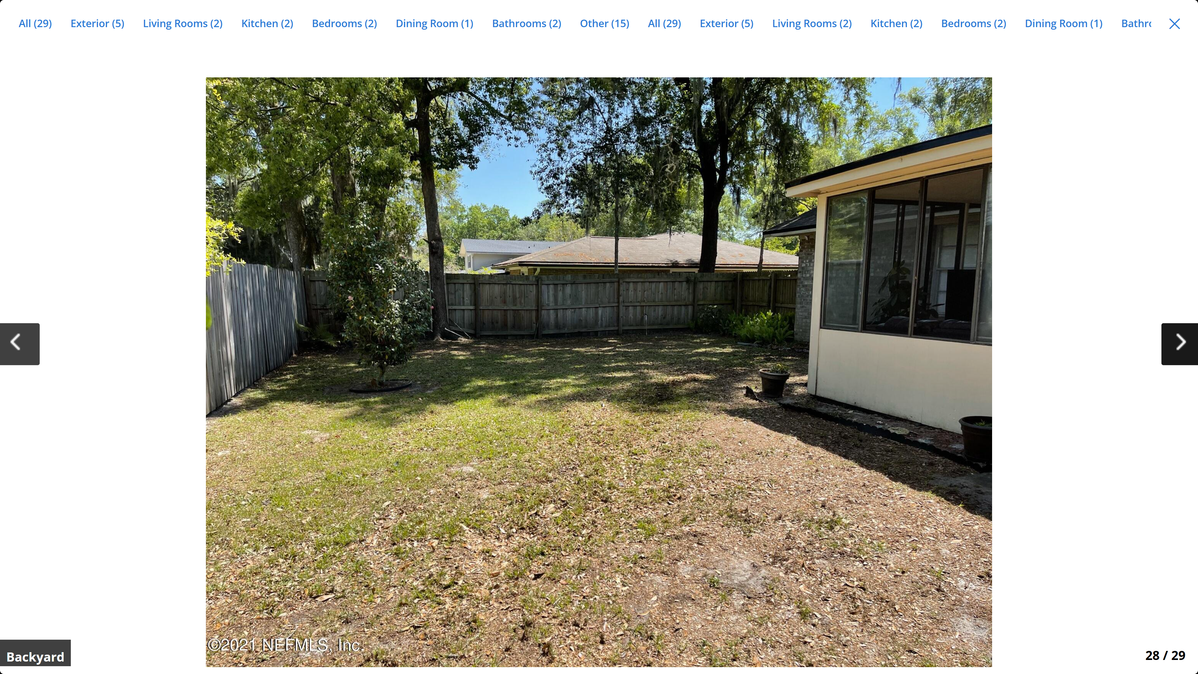 Backyard – open lawn with mature oak trees, wood privacy fence and screened Florida room