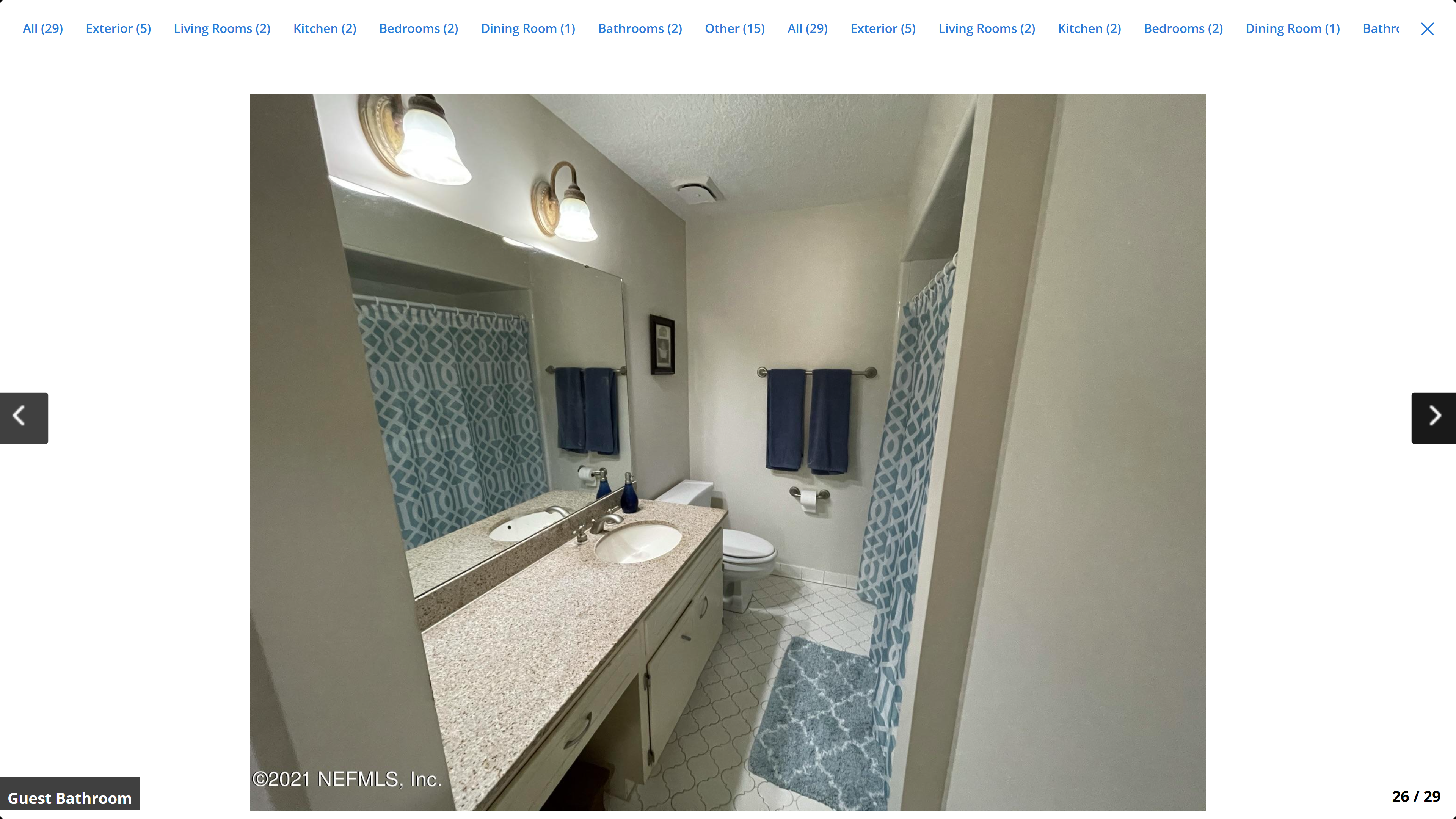 Guest bathroom – double-sink vanity with granite countertop, white tile floor, shower with curtain