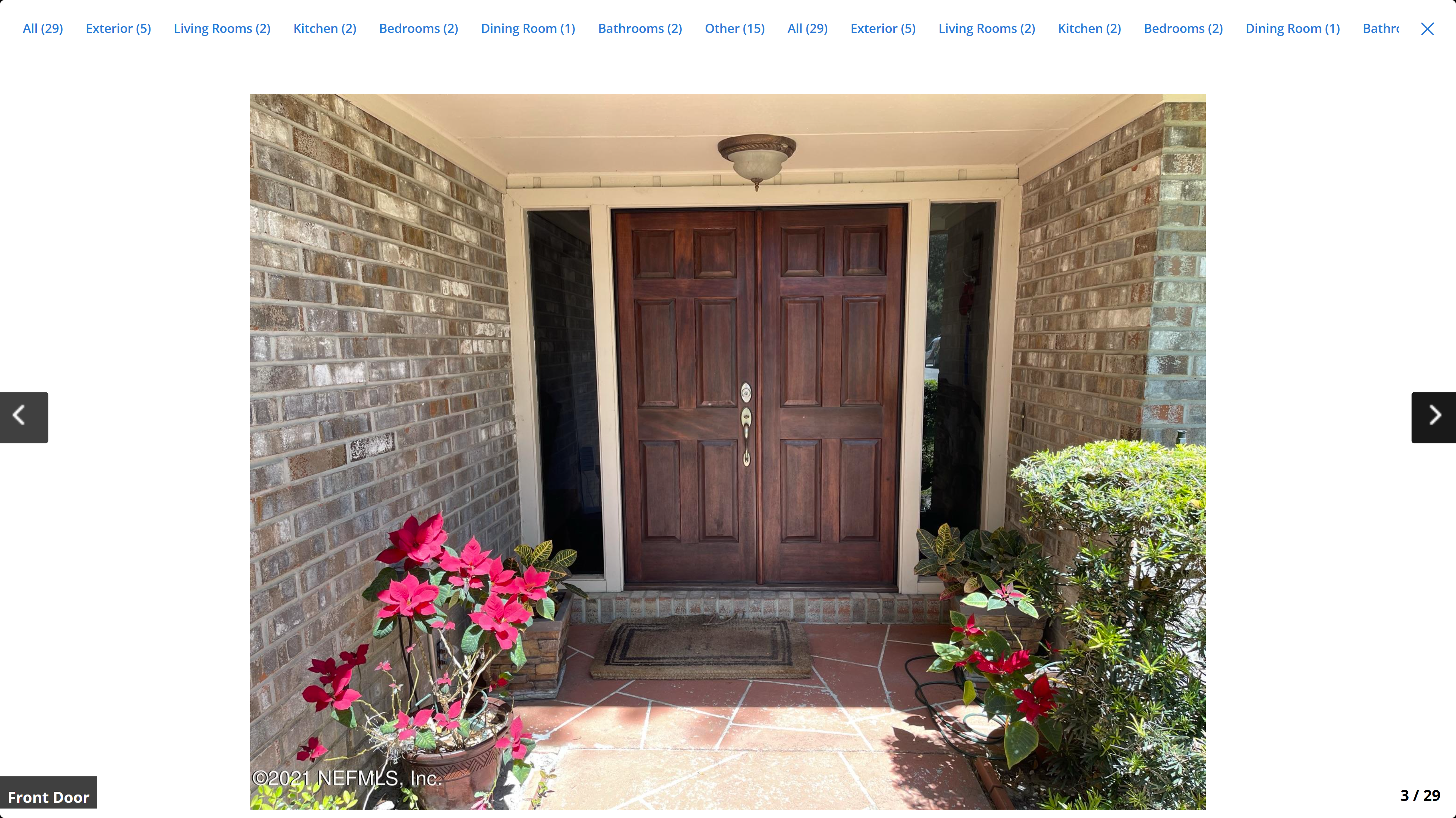 Front door – double mahogany wood doors with sidelights, brick surround and flowering plants