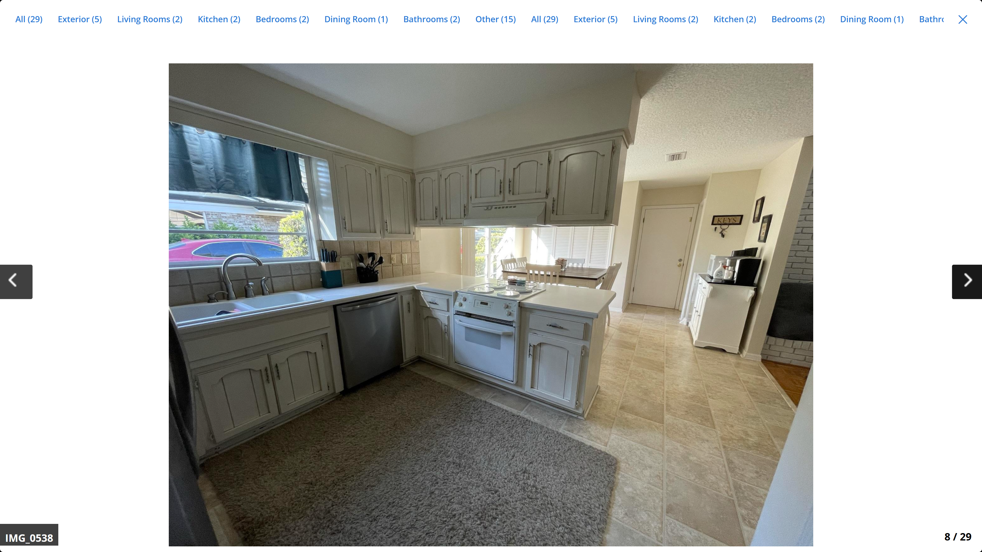 Kitchen – white raised-panel cabinets, tile countertops, stainless dishwasher, open to dining