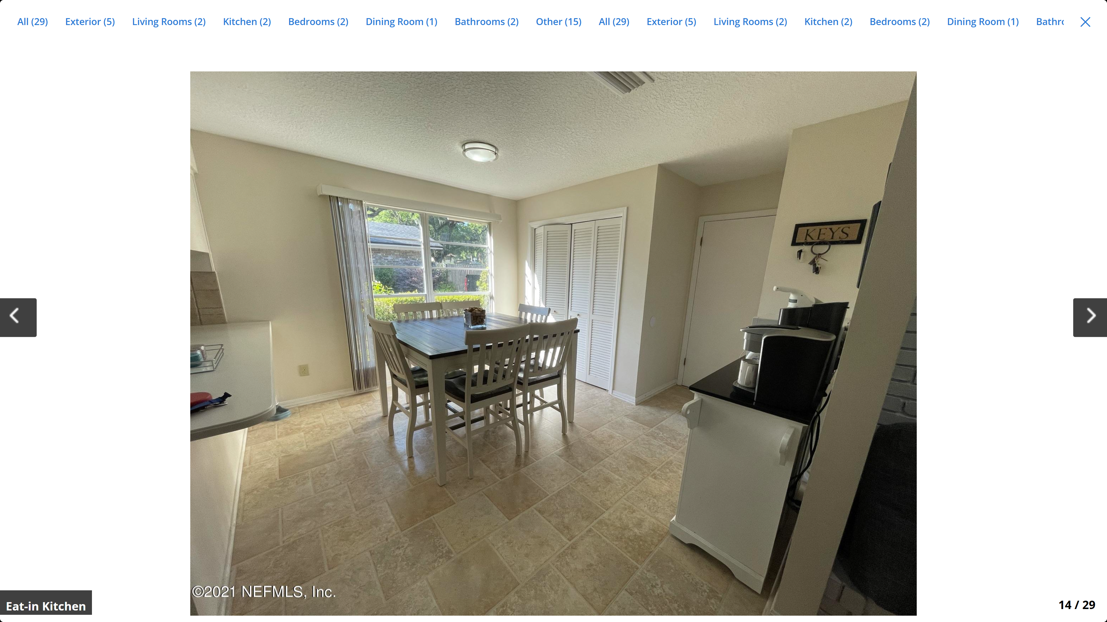 Eat-in kitchen / dining area – tile floor, large window with garden view, louvered pantry doors